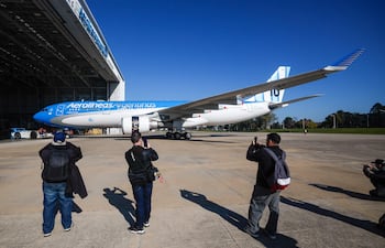 Personas observan un avión plateado de Aerolíneas Argentinas ingresando a un hangar este jueves, en el Aeropuerto Internacional de Ezeiza en José María Ezeiza (Argentina). La línea aérea estatal Aerolíneas Argentinas presentó el avión que llevará a la selección argentina de fútbol al Mundial 2026, con un diseño que incorpora la camiseta número 10 del capitán y figura del equipo, Lionel Messi. EFE/ Juan Ignacio Roncoroni