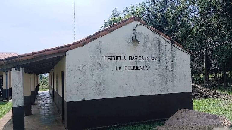 Fachada de la Escuela Básica N° 526 La Residenta, de paredes blancas y techo de tejas rojas, sin personas visibles.