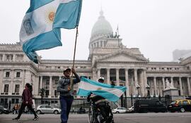 Personas sostienen banderas a las afueras del senado argentino.