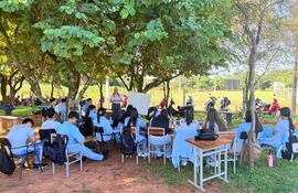 Estudiantes del colegio técnico Nuestra Señora de Lourdes desarrollan clases bajo los árboles mientras se aguarda la refacción de las aulas dañadas.