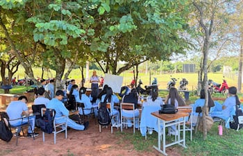 Estudiantes del colegio técnico Nuestra Señora de Lourdes desarrollan clases bajo los árboles mientras se aguarda la refacción de las aulas dañadas.