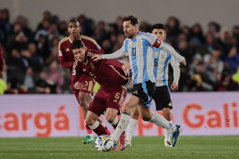 Lionel Messi (d), futbolista de la selección de Argentina, disputa el balón con Leonardo Flores, jugador de Venezuela, en el partido de la fecha 17 de las Eliminatorias Sudamericanas 2026 en el estadio Monumental, en Buenos Aires, Argentina.
