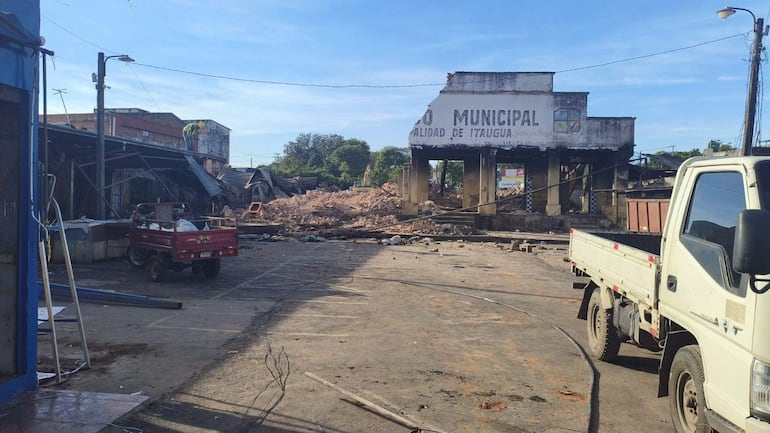 Un camión y un vehículo rojo en el desolado Mercado Municipal de Itauguá, con escombros y cables visibles en el entorno.