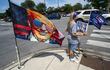 Una bandera de Trump ondea mientras una partidaria del ex presidente estadounidense sostiene un cartel. El expresidente Donald Trump, víctima ayer de un atentado fallido durante un mitin político en Butler (Pensilvania), pasó el domingo recluido en el club de golf de Bedminister, en Nueva Jersey, de su propiedad.