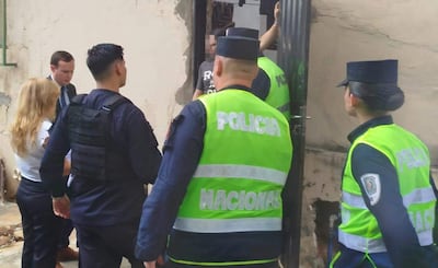Tres policías en uniforme junto a una mujer de blusa blanca y pantalones oscuros, en la entrada de un edificio en el centro de Asunción.