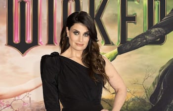 Idina Menzel en vestido negro asimétrico, con cabello suelto, mostrando confianza antes de su actuación.