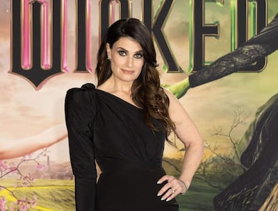 Idina Menzel en vestido negro asimétrico, con cabello suelto, mostrando confianza antes de su actuación.