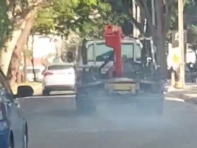 Grúa municipal tira humo negro.