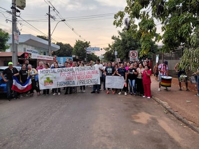 Grupo de manifestantes en la calle, sostenido banners, algunos con camisetas de fútbol, pidiendo un salario justo.