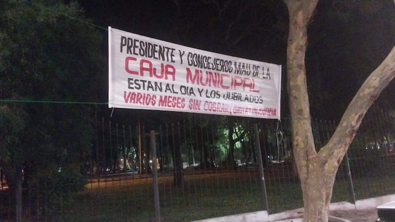 Cartel en el microcentro muestra reclamo sobre pagos a jubilados de la Caja Municipal, sin personas visibles en la imagen.