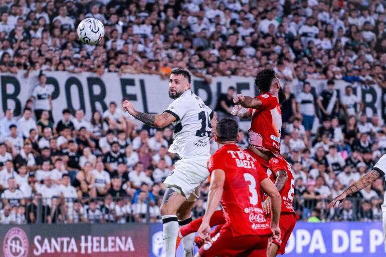 El argentino Lucas Pratto, jugador de Olimpia, cabecea el balón frente a la mira de Francisco Báez (3), futbolista de Sportivo Ameliano, en un partido por el torneo Apertura 2024 del fútbol paraguayo en el estadio Osvaldo Domínguez Dibb, en Asunción.