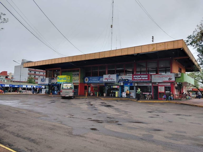 Terminal de Ómnibus de Encarnación en día nublado, con quioscos y buses en entrada. Sin personas claramente identificables.