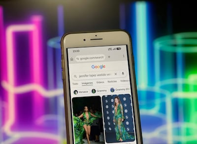 Pantalla de teléfono móvil mostrando búsqueda de Jennifer Lopez en vestido verde Versace, con fondo colorido.