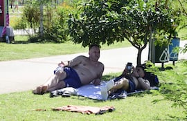 Hinchas argentinos se rebuscaban para guarecerse del calor en las escasas sombras que encontraron en la Costanera Norte de Asunción.