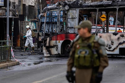 Un policía monta guardia mientras un perito forense camina junto a un autobús de la Red Metropolitana de Movilidad (RED) tras chocar con una furgoneta en el barrio Franklin, Santiago, Chile.