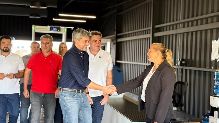Expresidente del Päraguay Mario Abdo Benítez saludando a funcionaria del Aeropuerto de Encarnación, con un grupo de políticos locales detrás.