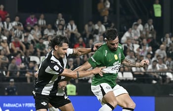 El delantero de Olimpia, Gabriel Ávalos conserva la posesión del esférico ante la marca del zaguero de Libertad, Nicolás Freire.