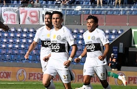 Bernardo Benítez, con camiseta blanca y número 37, celebra un gol junto a Gabriel Ávalos, en un ambiente de alegría deportiva.