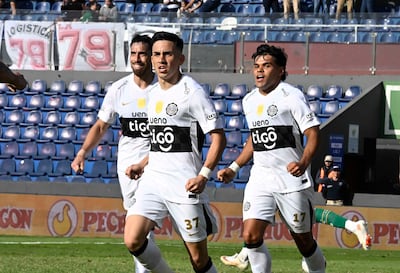 Bernardo Benítez, con camiseta blanca y número 37, celebra un gol junto a Gabriel Ávalos, en un ambiente de alegría deportiva.