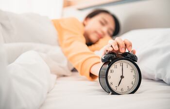 Una mujer apaga su reloj despertador.