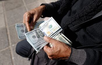 Un cambista informal sosteniendo dólares en el centro de Asunción.