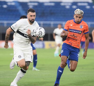 El delantero de Olimpia, Lucas Pratto (34 años) intenta escapar con el balón ante la marca del defensor Miguel Ángel Barreto (26).