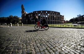 Una persona monta en bicicleta ante el Coliseo romano durante el nuevo confinamiento, en Roma.