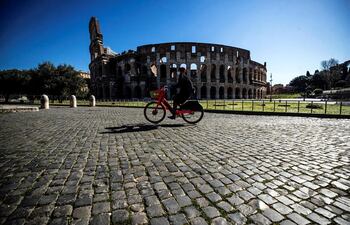 Una persona monta en bicicleta ante el Coliseo romano durante el nuevo confinamiento, en Roma.