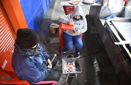 Funcionarias de un local de venta de hamburguesas sobre la avenida Artigas intentar guarecerse del frío esta madrugada.