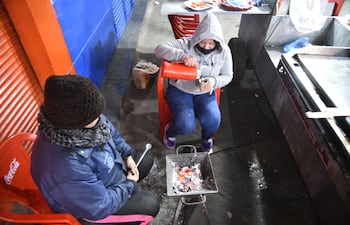 Funcionarias de un local de venta de hamburguesas sobre la avenida Artigas intentar guarecerse del frío esta madrugada.
