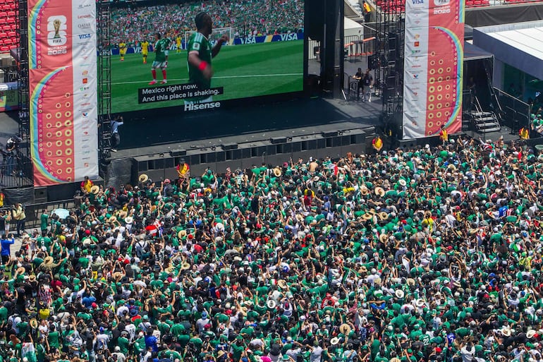 Aficionados de México festejan el gol de Julián Quiñones en el fan fest, en la plancha del Zócalo capitalino.