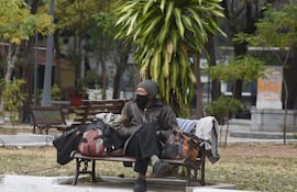 Un hombre abrigado durante el ingreso de un frente frío, en una plaza de Asunción.