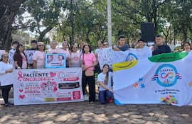 Grupo de al menos 20 personas con camisetas blancas, sosteniendo pancartas sobre salud y autismo en un parque.