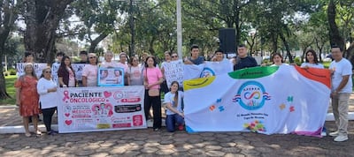 Grupo de al menos 20 personas con camisetas blancas, sosteniendo pancartas sobre salud y autismo en un parque.