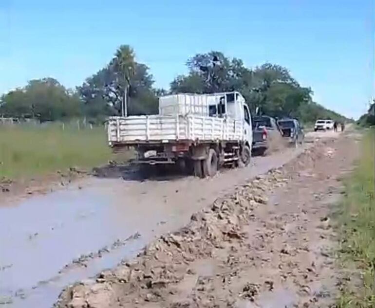 Camión de carga atascado en el barro, es ayudado por otros automovilistas.