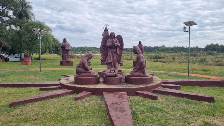 Estatuas de un ángel y figura maternal en un entorno natural con vegetación y cielo nublado.
