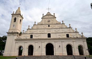 Iglesia Santísima Trinidad mostrada sin personas, con fachada blanca, campanario y cielo nublado como telón de fondo.