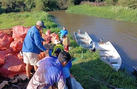 Los voluntarios de la Asociación de Pescadores alzan en un camión volquete los desechos recolectados del Tapiracuai.