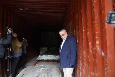 Isaías Fretes con chaqueta oscura y camisa blanca, observa el interior de un contenedor, rodeado de fotógrafos en un ambiente de inspección.