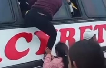 Una pasajera baja por la ventanilla del ómnibus que quedo atascado en un puente en la zona de Curuzú Ava distrito de Cerrito.