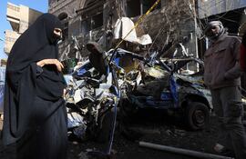 Varias personas en el sitio de un bombardeo estadounidense que mató al menos a 12 personas ayer martes en Saná, Yemen.