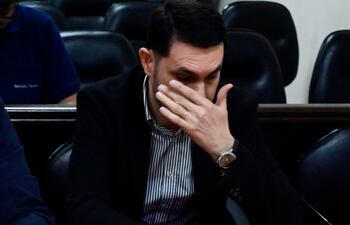 Alba Zaracho con chaqueta oscura y blusa blanca, mirando reflexiva a Hernán Rivas, que se cubre el rostro con la mano.