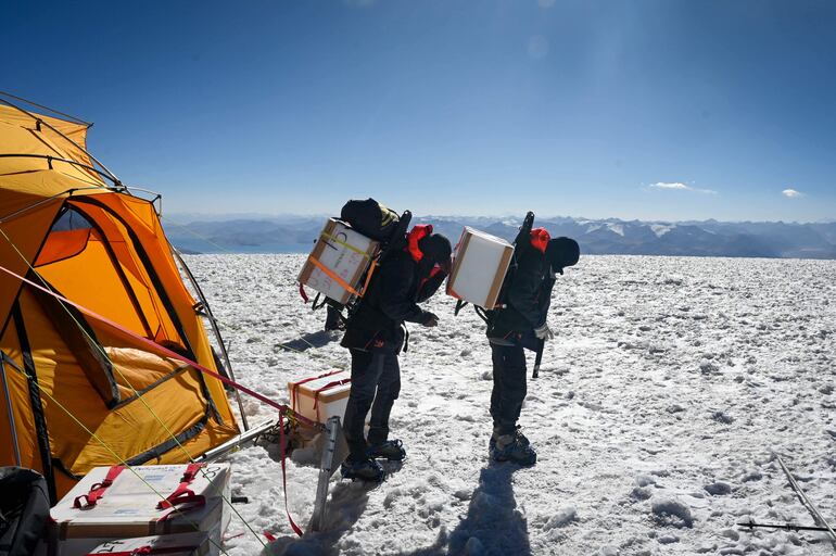 Dos miembros de la expedición 'Pamir-Ice-Memory' descienden el glaciar de Pamir, llevando muestras de núcleos de hielo en una caja refrigerada hacia el campamento base, en Kon Chukurbashi, Tayikistán oriental, el 24 de septiembre de 2025.