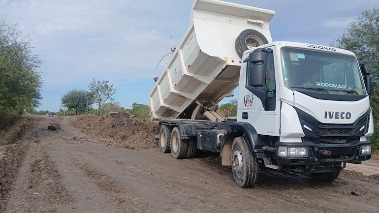 Camión volquete volcando material para aumentar altura del muro