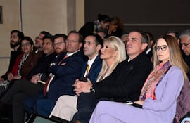 Soledad Núñez con chaqueta roja y Rafael Filizzola en auditorio, ambos atentos durante la presentación en evento formal interno.