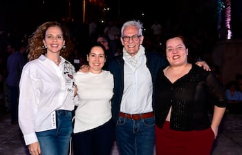Daniel Nasta con camisa azul y chaqueta oscura, y tres mujeres sonrientes, todas vestidas de blanco y negro, en evento al aire libre.