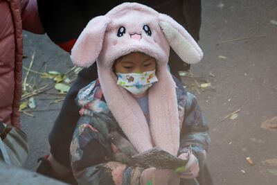Una niña con mascarilla sale de un colegio en Pekín, China.