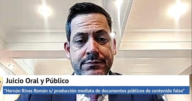 Hombre de barba con chaqueta formal, expresión seria en sala de audiencias. Texto visible sobre el juicio.