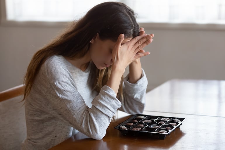 Mujer se esfuerza por no comer chocolates.