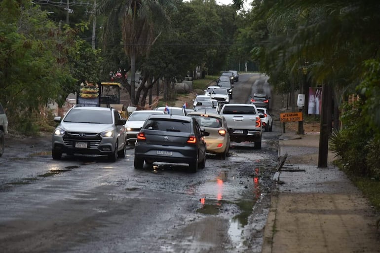 Carretera con tráfico moderado de coches en ambas direcciones, letrero sobre doble sentido visible a un lado.